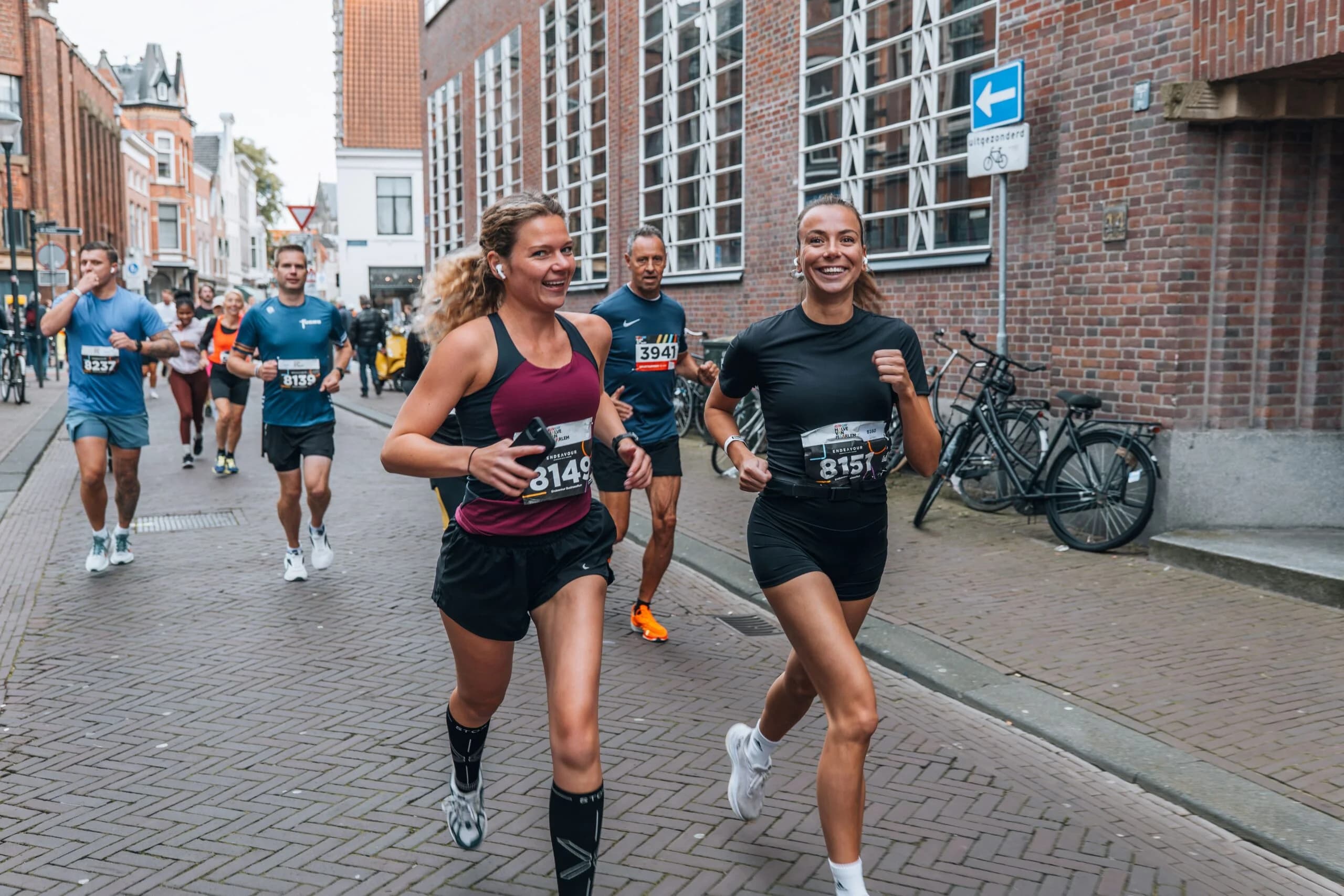 Twee vrouwen rennen door het centrum van Haarlem tijdens de halve marathon van Haarlem.