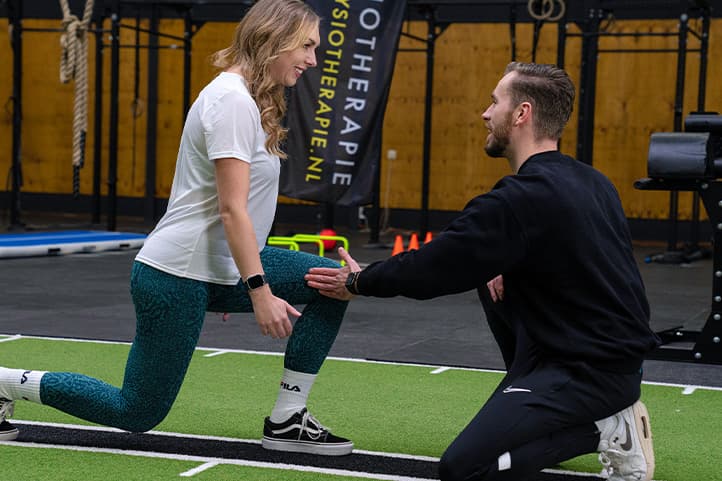 Een fysiotherapeut begeleidt een sporter tijdens een oefening.