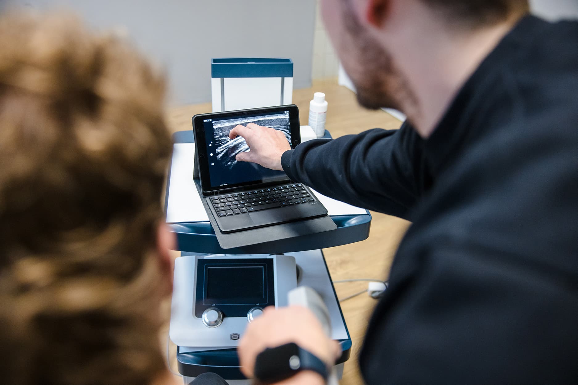 Fysiotherapeut Joffrey legt uit wat er in de gemaakte echo te zien is.